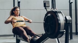 A woman using a rowing machine in the gym