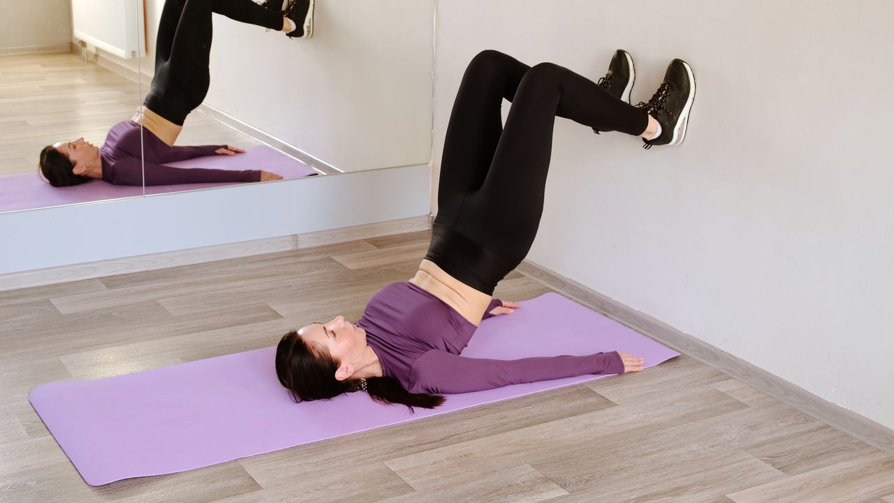 Woman in a fitness studio exercising with her feet resting on a wall